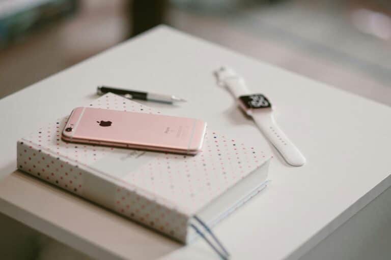 rosegoldenes iPhone 6s auf Buch in der nähe der Apple-watch