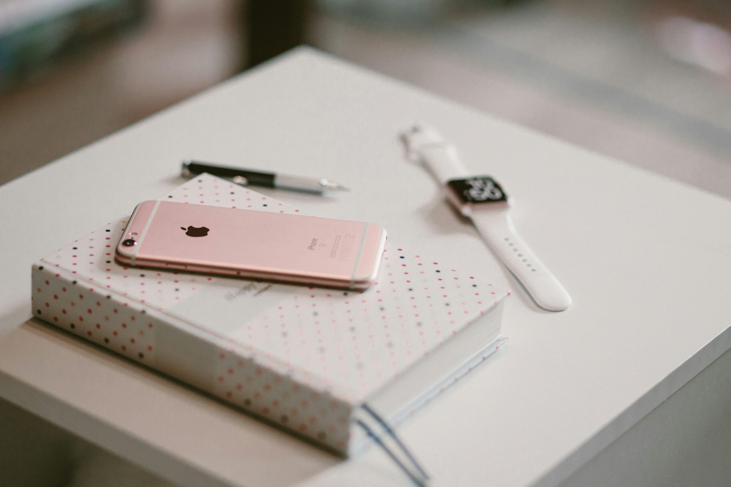 rosegoldenes iPhone 6s auf Buch in der nähe der Apple-watch