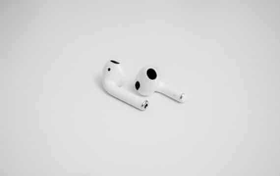 Weiße AirPods liegen minimalistisch auf hellem Hintergrund.