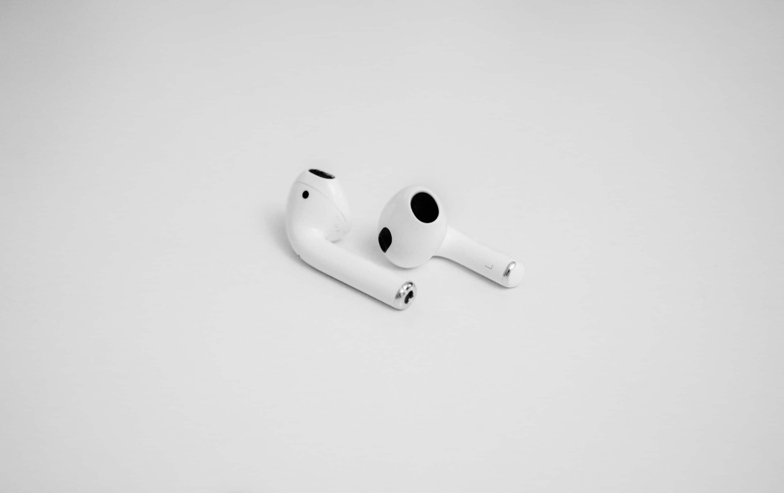Weiße AirPods liegen minimalistisch auf hellem Hintergrund.