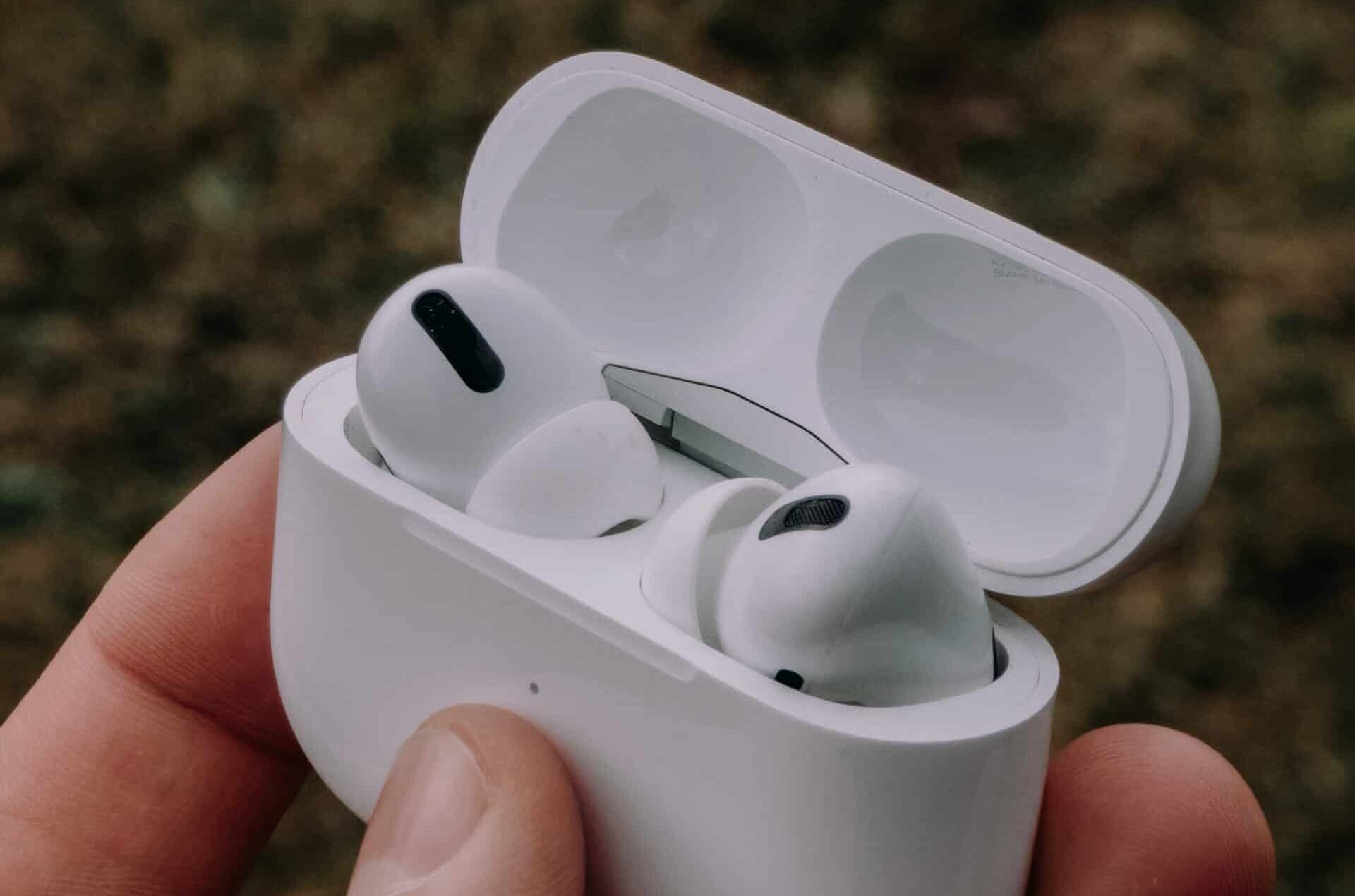 Weiße AirPods in geöffnetem Ladecase werden in der Hand gehalten.